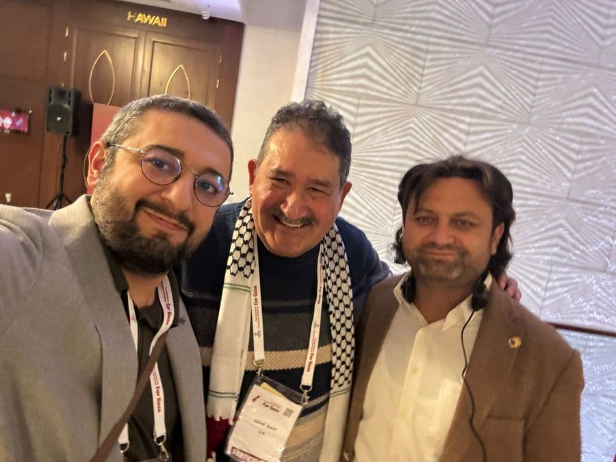 Gazian team members at conference wearing 'For Gaza' lanyards — real people behind the mission
